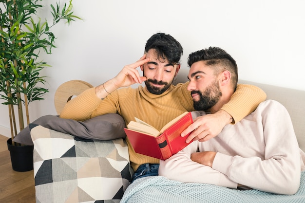 Uomo che guarda il suo fidanzato leggendo il libro a casa