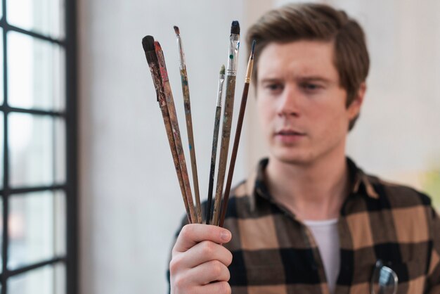 Man looking at his painting brushes