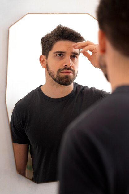 Мужчина смотрит в зеркало сбоку