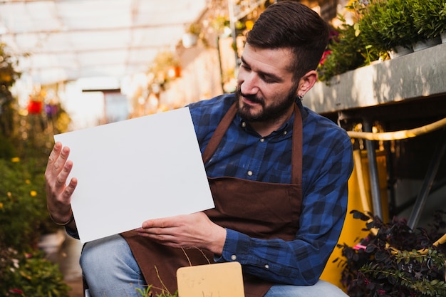 Man looking at paper sheet in greenhouse