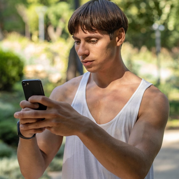 エクササイズ中に屋外でスマートフォンを見ている男