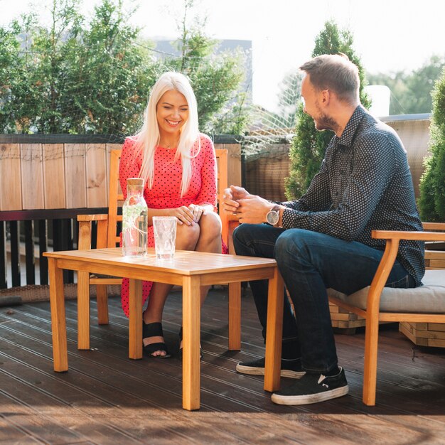 Man looking at smiling young woman sitting on rooftop