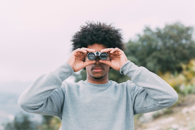 Foto gratuita uomo che guarda attraverso il binocolo