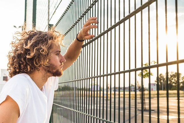 Foto gratuita uomo che guarda attraverso il recinto