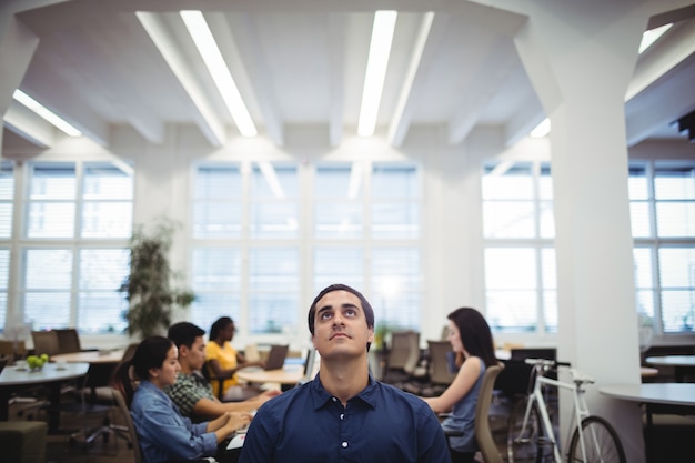 Foto gratuita uomo alzando lo sguardo, mentre i colleghi che lavorano in background