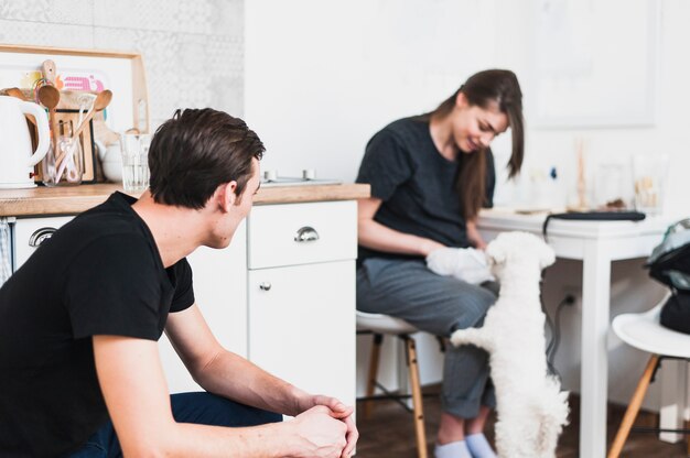 A man looking at woman playing with toy poodle in home