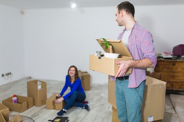 Man looking at woman sealing boxes