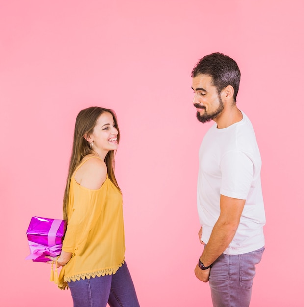 Free photo man looking at wrapped gift hiding from boyfriend