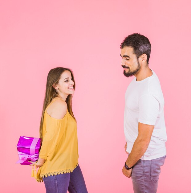 Man looking at wrapped gift hiding from boyfriend