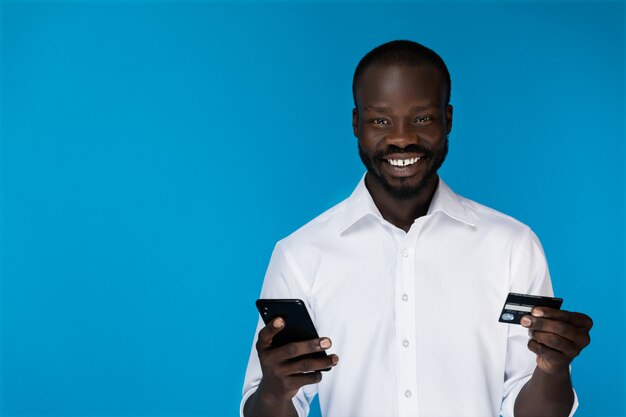 Man looks at the camera and holds a phone and credit card