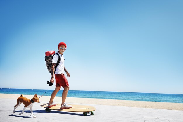 남자는 그의 강아지와 함께 해변에서 산타를 타는 롱보드처럼 보입니다.