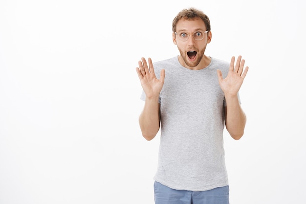 Man loosing speech from exciting news raising palms in surrender dropping jaw and staring entertained and amazed holding breath being thrilled while posing