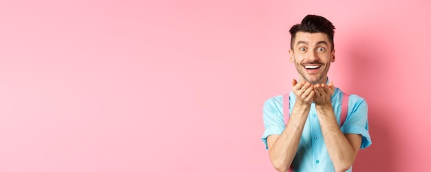 Foto gratuita uomo innamorato che soffia bacio alla macchina fotografica e sorridente appassionato guardando l'amante felice godendo san valentino