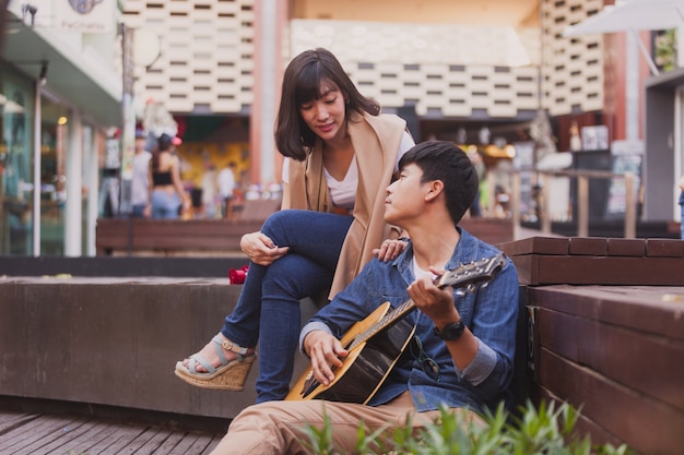 Man in love playing guitar sitting on the floor at his girlfriend