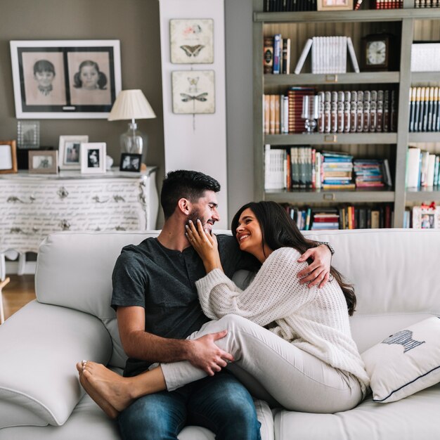 Man loving her girlfriend sitting on sofa at home