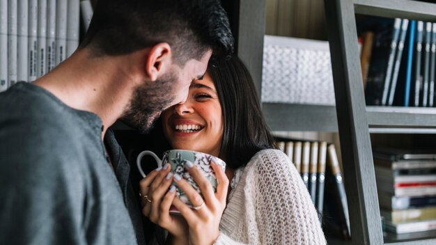 コーヒーカップを持っている彼女の笑顔の女性を愛する男