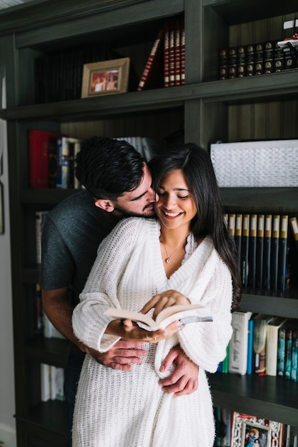 Man loving her wife holding an open book in front of bookshelf