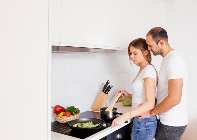 man loving his wife coking food on new electric stove with induction cooktop in kitchen