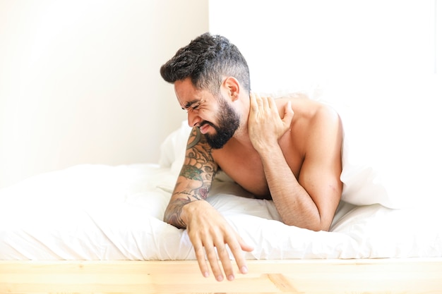 Man lying on bed suffering from neck pain