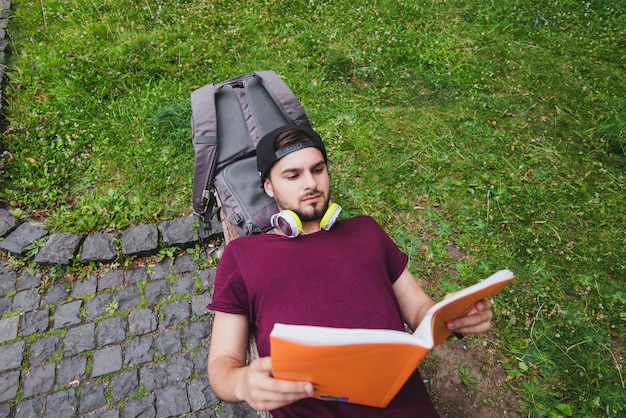 Free photo man lying on bench in park reading