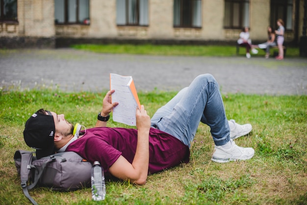 Free photo man lying on grass reading