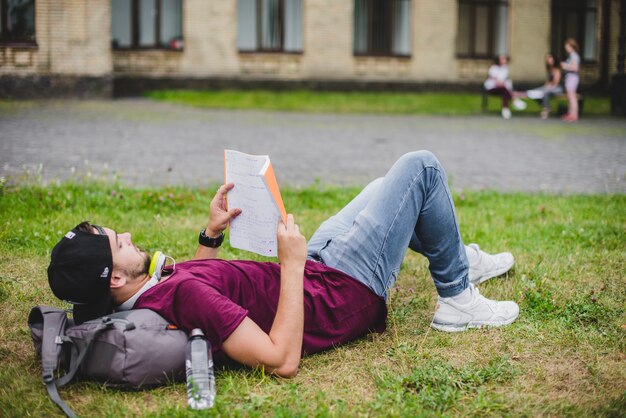 Man lying on grass reading