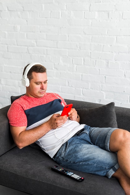 Man lying on sofa listening to music on headphone