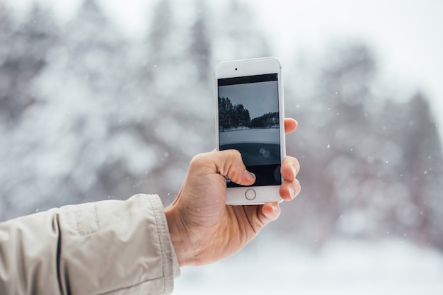 Man makes photo of snow winter on smartphone