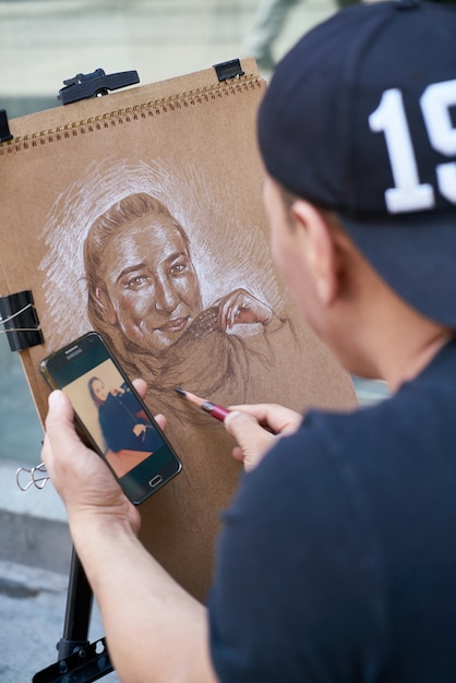 Foto gratuita uomo che fa un dipinto con un cellulare in mano