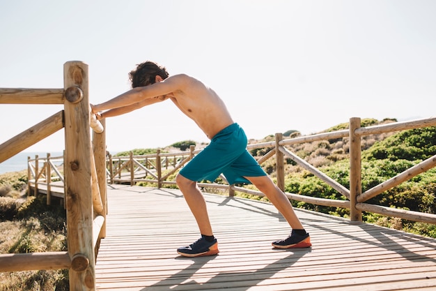 ビーチでストレッチ運動をする男