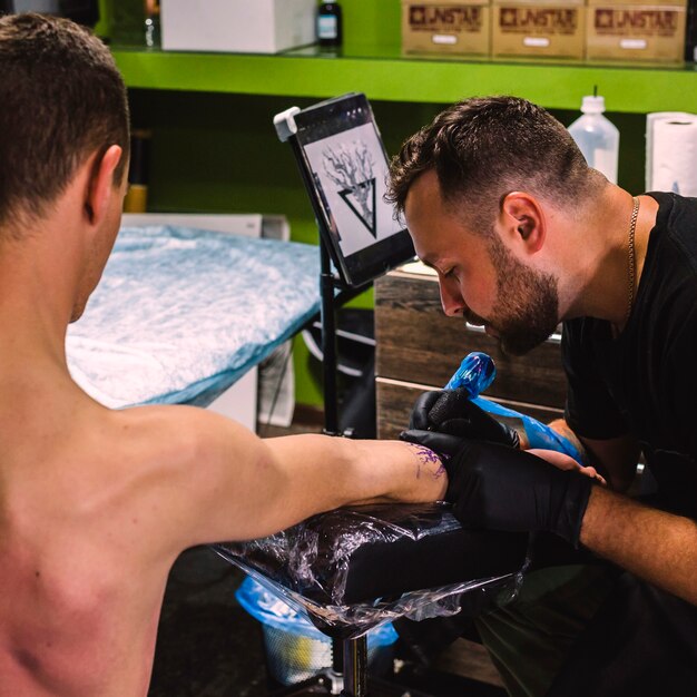 Man making tattoo on arm in studio