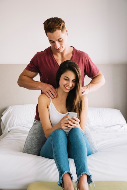 Man massaging shoulder of woman on bed 