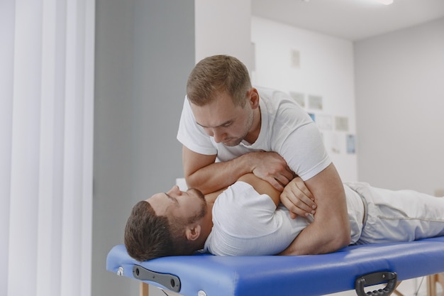 Foto gratuita uomo nell'ufficio medico. il fisioterapista sta riabilitando la schiena.