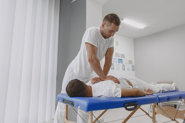 Man in the medical office. Physiotherapist is rehabilitating back.