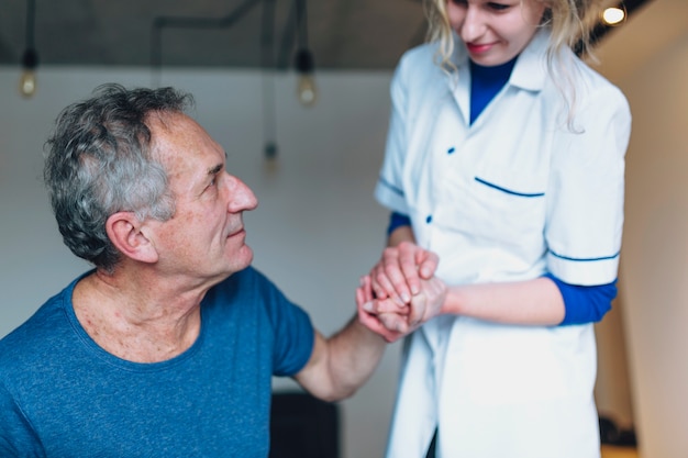 Free photo man and nurse holding hands in old age home