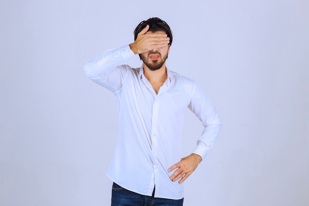 Man observing outside through his fingers or hiding his face.