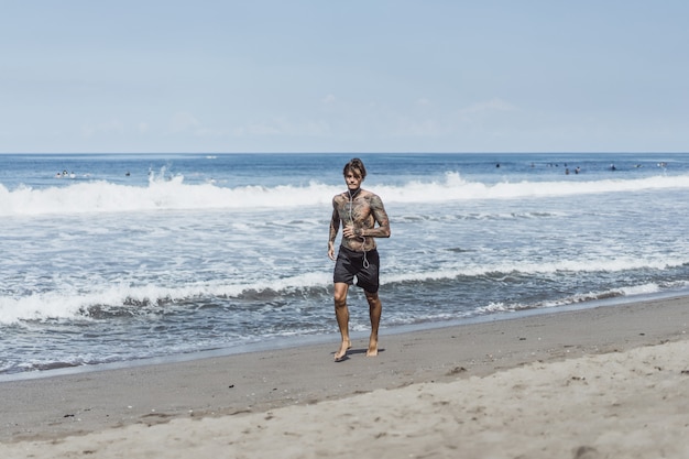 Un uomo sulla costa dell'oceano che corre lungo la riva del mare