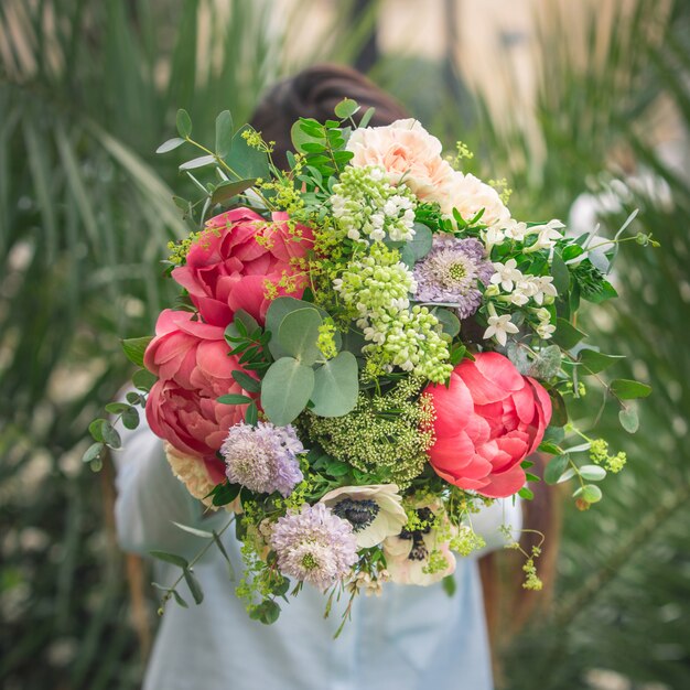 A man offering a bouquet of colorful summer flowers.