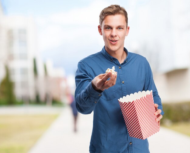 Man offering popcorn while holding a packet of popcorn