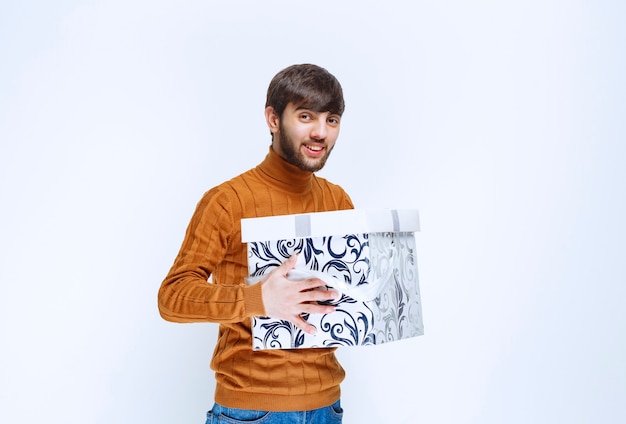 Man offering or received a white gift box with blue patterns.