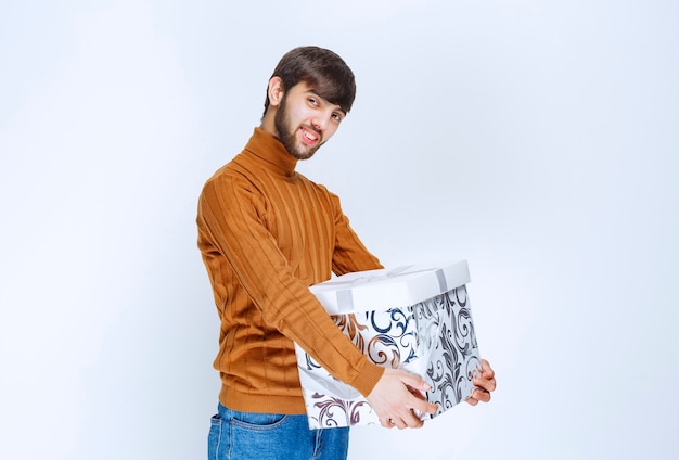 Man offering or received a white gift box with blue patterns.