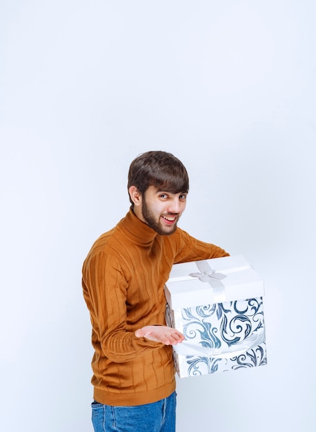 Foto gratuita l'uomo offre o riceve una confezione regalo bianca con motivi blu.
