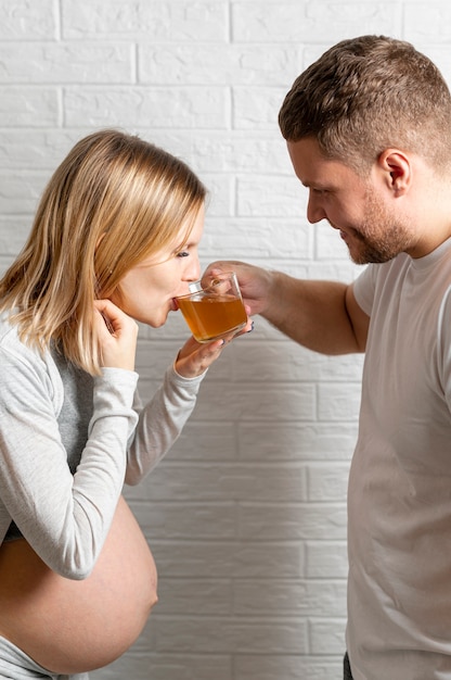 Free photo man offering a tea to his pregnant wife