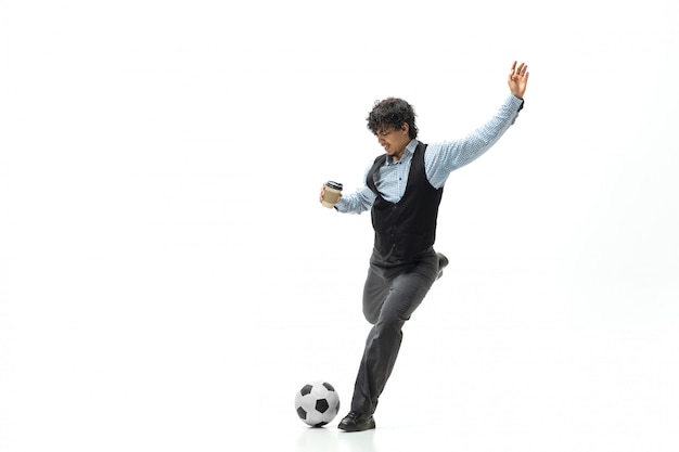 Man in office clothes playing football or soccer with ball on white space. Unusual look for businessman in motion, action. Sport, healthy lifestyle.