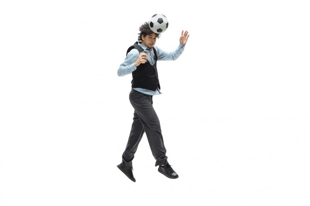 Man in office clothes playing football or soccer with ball on white space. Unusual look for businessman in motion, action. Sport, healthy lifestyle.