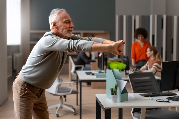 Foto gratuita uomo in ufficio che si allunga durante una giornata lavorativa