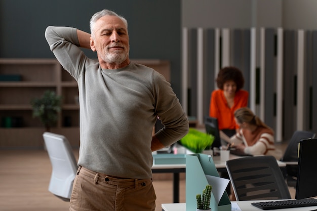 Foto gratuita uomo in ufficio che si allunga durante una giornata lavorativa