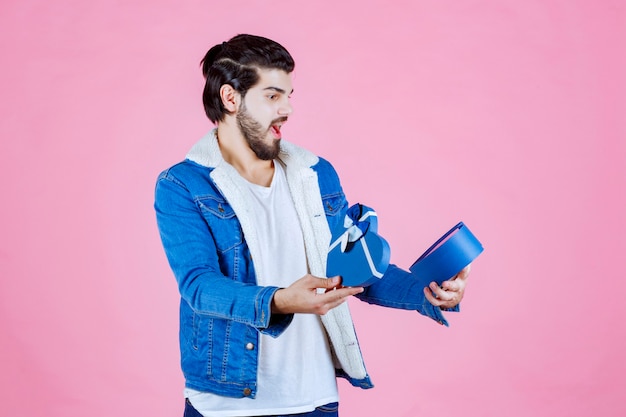 Free photo man opening a gift box and looks surprized