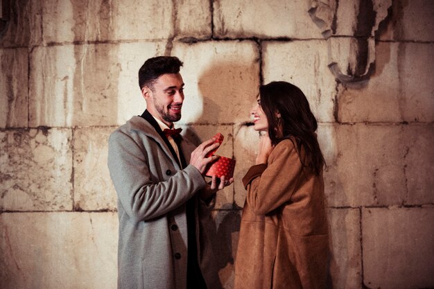 Man opening gift box to pretty woman in street