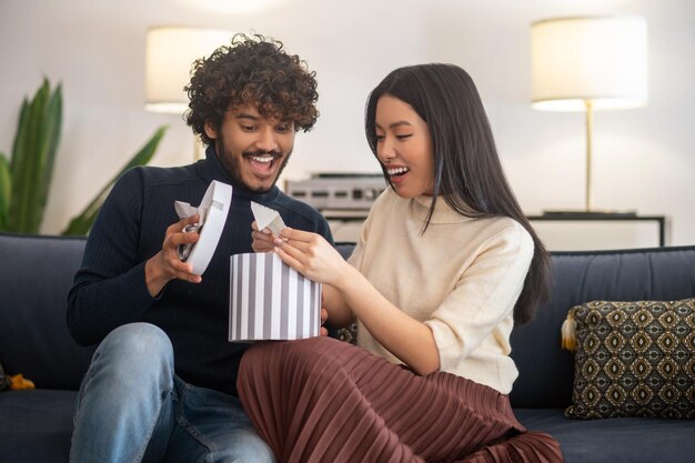 Man opening gift box and woman holding note